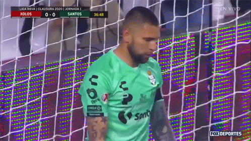 A Man In A Green Santos Jersey Is Standing In Front Of A Soccer Net GIF