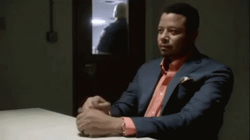 A Man In A Green Scrub Suit Is Sitting At A Table With Another Man . GIF