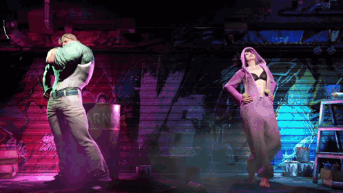 A Man In A Green Shirt And A Woman In A Purple Hoodie Are Dancing In A Dark Room GIF