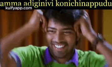a man in a green shirt and purple shirt is smiling and holding his head .