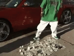 A Man In A Green Shirt And White Pants Is Standing On A Pile Of Money . GIF