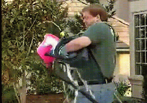 A Man In A Green Shirt Is Carrying A Pink Bag GIF