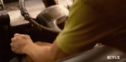 A Man In A Green Shirt Is Driving A Car With Netflix Written On The Bottom Of The Screen GIF