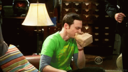 A Man In A Green Shirt Is Eating A Bag Of Food . GIF