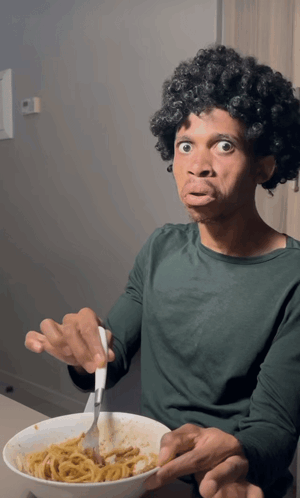 A Man In A Green Shirt Is Eating Spaghetti With A Fork GIF