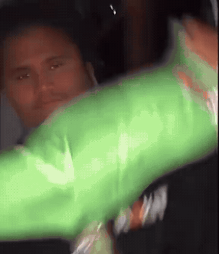 A Man In A Green Shirt Is Holding A Green Object GIF