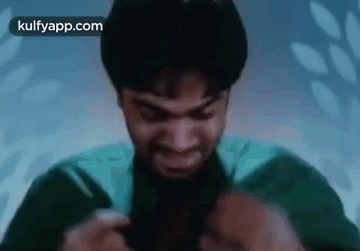 A Man In A Green Shirt Is Holding A Knife In His Hand And Smiling . GIF