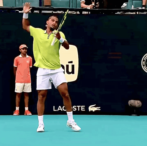 a man in a green shirt is holding a tennis racquet in front of a lacoste sign
