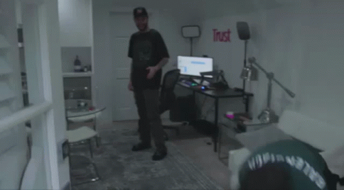 A Man In A Green Shirt Is Laying On The Floor Next To A Broken Monitor . GIF