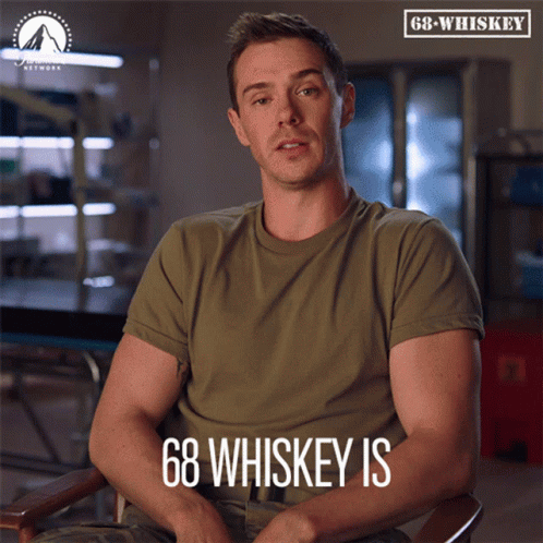 Man In Green Shirt Sitting With 68 Whiskey Above GIF