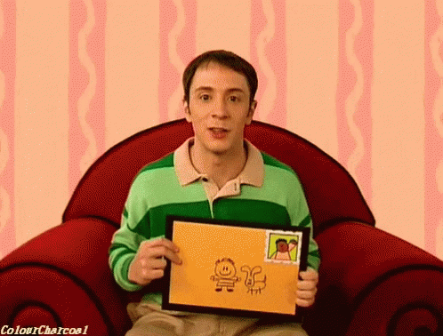 a man in a green shirt is sitting in a red chair holding a drawing