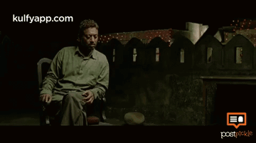 A Man In A Green Shirt Is Sitting In Front Of A Fence With The Website Kulfyapp.com On The Bottom Right GIF