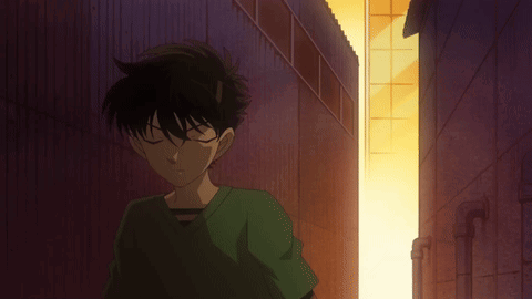 A Man In A Green Shirt Is Standing In A Dark Alleyway GIF