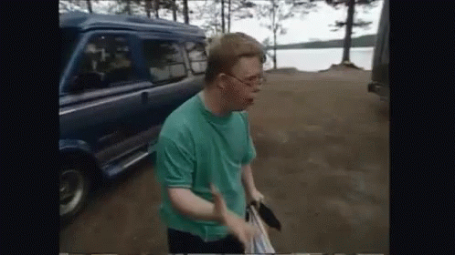 A Man In A Green Shirt Is Standing In Front Of A Van GIF