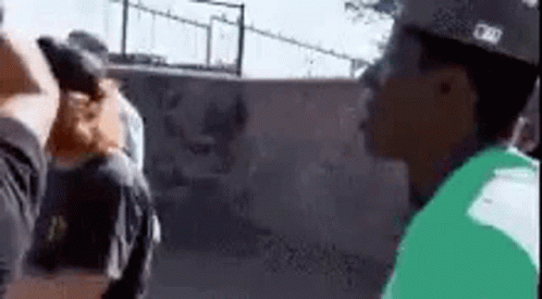 A Man In A Green Shirt Is Standing Next To A Man In A Black Shirt . GIF