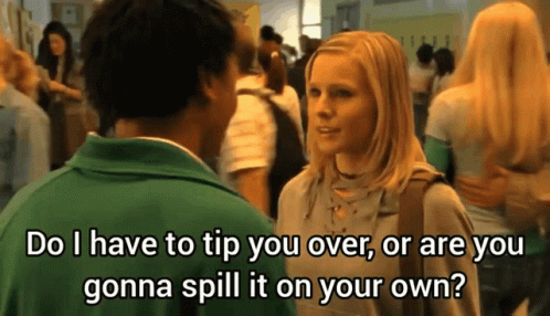 A Man In A Green Shirt Is Talking To A Blonde Woman In A Crowded Hallway GIF