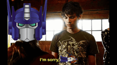 A Man In A Green Shirt Says I 'M Sorry In Front Of A Robot Head GIF