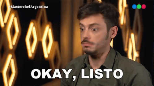 A Man In A Green Shirt Says Okay Listo In Front Of A Neon Sign GIF