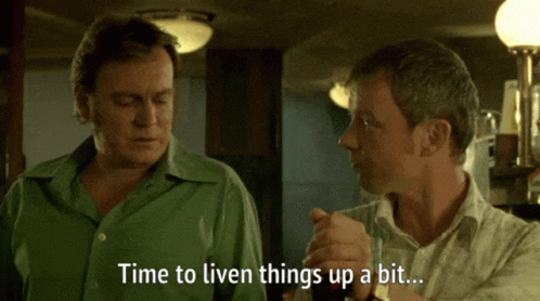 a man in a green shirt says " time to liven things up a bit " to another man