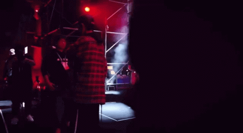 A Man In A Green Shirt Stands In Front Of A Crowd Of People GIF