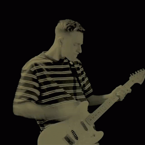 A Man In A Green Striped Shirt Is Playing A Guitar GIF