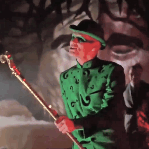 A Man In A Green Suit And Hat Is Holding A Gold Cane GIF