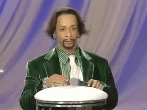 A Man In A Green Suit And Tie Holds A Microphone GIF