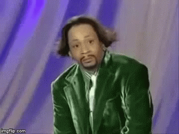 A Man In A Green Suit And Tie Is Standing In Front Of A Purple Wall . GIF