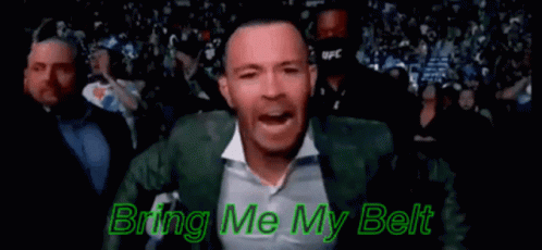 A Man In A Green Suit And White Shirt Is Standing In Front Of A Crowd And Singing . GIF