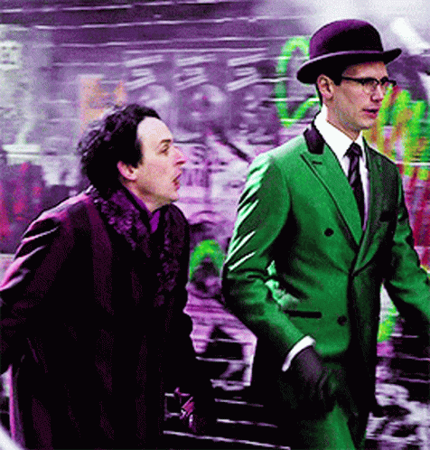 A Man In A Green Suit Stands Next To Another Man GIF