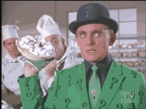 A Man In A Green Suit With A Question Mark On His Jacket GIF