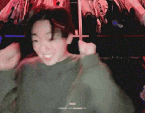 a man in a green sweater is making a funny face while dancing .
