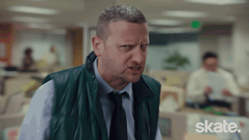 A Man In A Green Vest And Tie Is Making A Funny Face And The Word Skate Is Visible In The Corner GIF