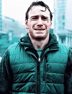 A Man In A Green Vest Is Crying While Standing In Front Of A Building . GIF