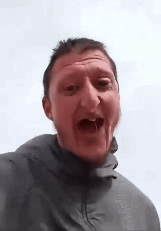 A Man In A Grey Jacket Is Making A Funny Face . GIF