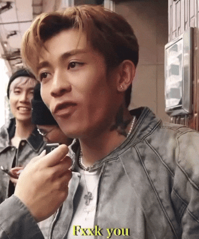 A Man In A Grey Jacket Says Fxxxk You In Yellow Letters GIF