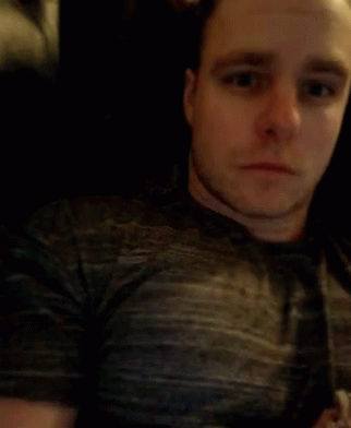 A Man In A Grey Shirt Is Blowing His Nose With A Tissue GIF