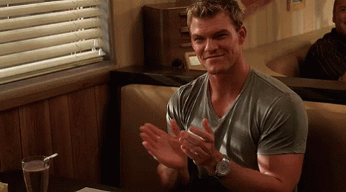 A Man In A Grey Shirt Is Clapping His Hands In A Diner . GIF