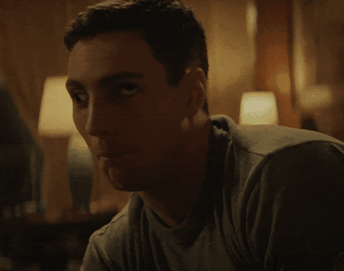 Man In Grey Shirt Looking At Camera GIF