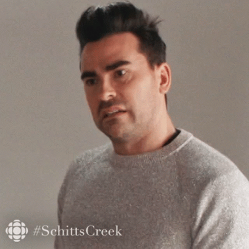 A Man In A Grey Sweater Is Looking At The Camera . GIF