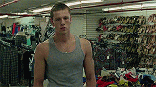 A Man In A Grey Tank Top Is Standing In A Store Full Of Shoes GIF