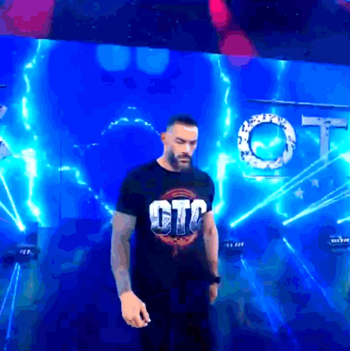 A Man In A Gtc Shirt Stands In Front Of A Blue Background GIF