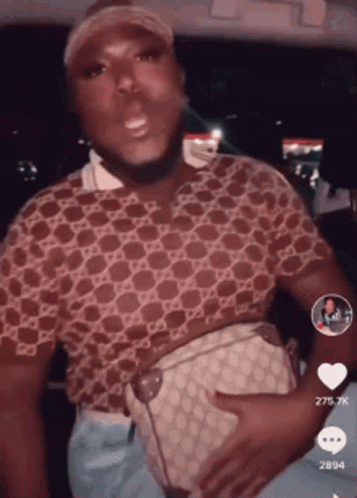 A Man In A Gucci Shirt Is Holding A Purse On His Stomach GIF