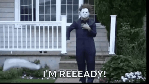a man in a halloween costume is standing in front of a house with his hand on his chest .