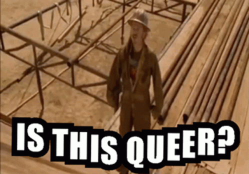 A Man In A Hard Hat Stands In Front Of A Wooden Structure With The Words Is This Queer Written Below Him GIF