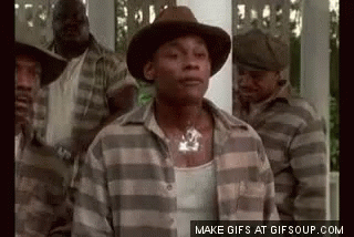 A Man In A Hat And Plaid Shirt Is Standing In Front Of A Group Of Men In Striped Shirts . GIF