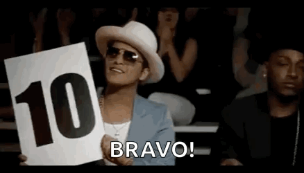 A Man In A Hat And Sunglasses Is Holding A Sign That Says `` Bravo '' . GIF