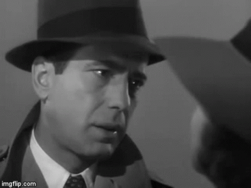 a man in a hat and tie is looking at another man in a suit .