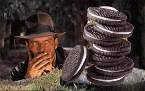 A Man In A Hat Is Covering His Mouth Behind A Stack Of Oreos GIF