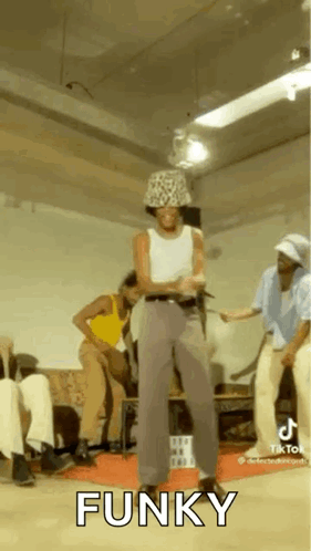 A Man In A Hat Is Dancing In A Room With Other People And The Word Funky Is On The Screen . GIF